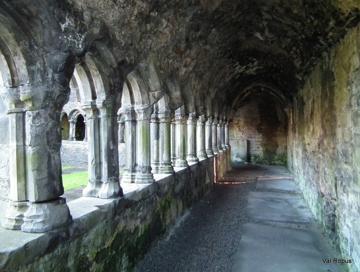 View of an ancient stone corridor with arched columns and a textured ceiling, showcasing a historical architectural design.