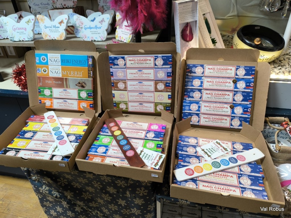 Display of incense boxes and sticks on a table, featuring various scents and brands, including Nag Champa and Palo Santo, set against a festive background with decorations.