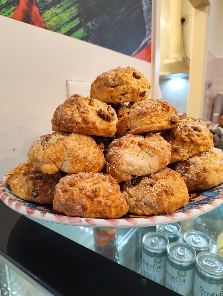 A stack of freshly baked scones sprinkled with sugar, displayed on a decorative plate.