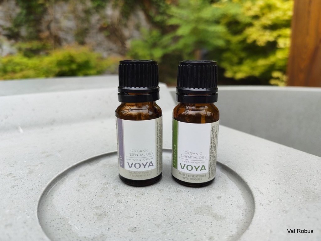 Two bottles of organic essential oils placed on a concrete surface, labeled Lavender & Rosemary and Lime & Mandarin.