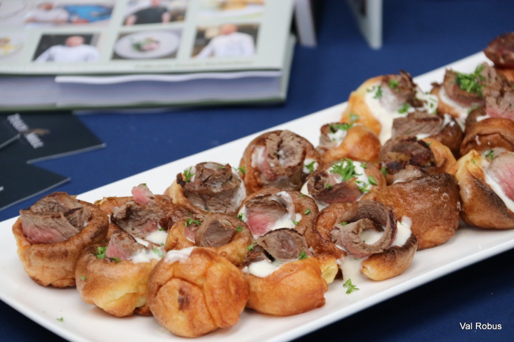 A platter of rolled meat and Yorkshire pudding bites topped with a dollop of sauce and garnished with parsley.